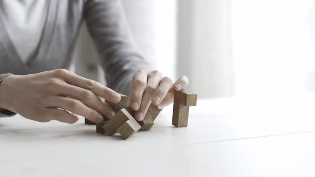 Woman playing with a wooden brain teaser puzzle