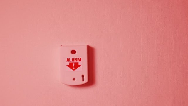 hand push white alarm button on the grey wall. after that turns on red siren lights