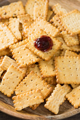 Crackers with cherry jam on a wooden plate on a wooden background. Rustic style