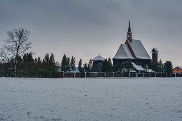 zimowy wiejski krajobraz z nowoczesnym kościołem, otoczony płotem kościół ze spadzistym dachem przypominającym drewniane świątynie © Jarek Witkowski