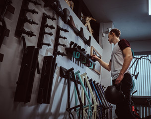 Young man holding a protective helmet and choosing parts for his BMX in bicycle shop