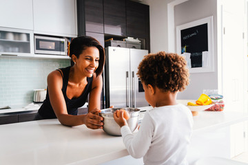 Smiling mother with son preparing food in kitchen at home