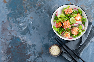 Healthy lunch salad with baked salmon fish, fresh radish, lettuce and lime. Top view