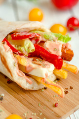 Wrap with cheese, pepper, French fries. Closeup.