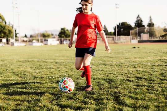 Full Length Of Girl Kicking Soccer Ball On Field