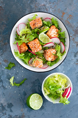Healthy lunch salad with baked salmon fish, fresh radish, lettuce and lime. Top view