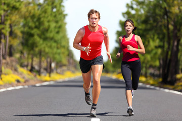 Running fitness couple of runners doing sport on road outdoor. Active living man and woman jogging training cardio in summer outdoors nature. Asian girl, caucasian athletes.