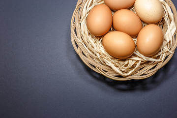 Chicken eggs in basket on dark background. Top view with copy space
