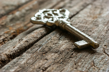 ancient, old metal key on chestnut rustic wooden background. Antique concept