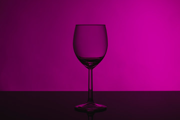 Wine glass on a pink background on a glossy black glass