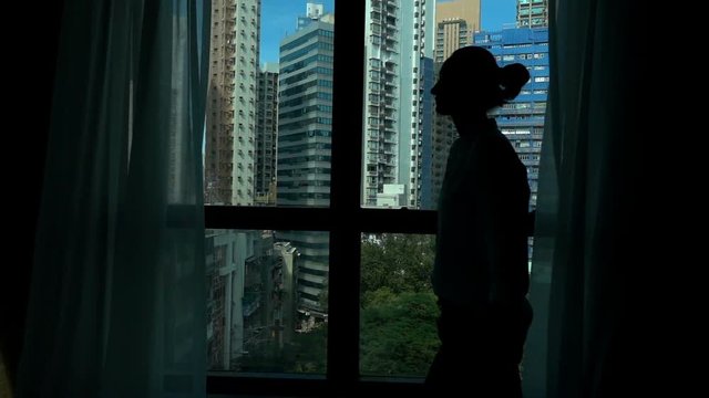 Silhouette of woman walking by the window at home, slow motion
