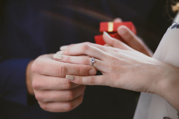 Closeup photo of groom putting ring on bride's finger