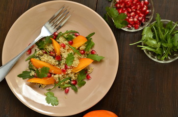 Quinoa salad with persimmon, pomegranate and fresh herbs, top view, copy space