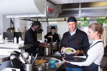 Staff of restaurant with chef working