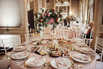 Wedding dinner table setting. Pink flowers and decor details on festive served tables