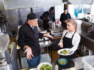 Waitress with dish talking with puzzled chef