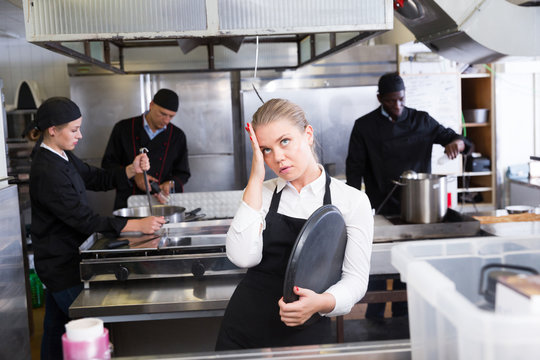 Unhappy waitress waiting dishes in kitchen