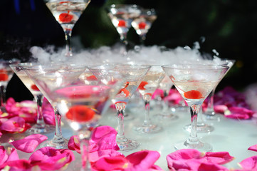 A slide of champagne with dry ice and smoke at the solemn event. Pyramid of glasses with alcohol and cherries.