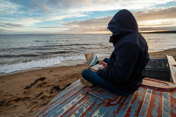 Anonymous in the internet. Single programmer or hacker working on the islands beach.