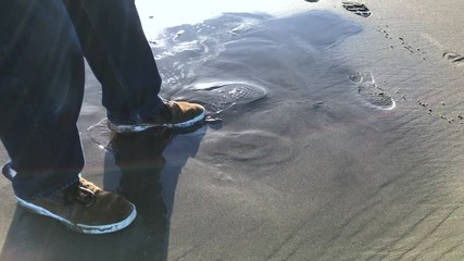 Man testing beach for quicksand danger by cautiously stepping on it