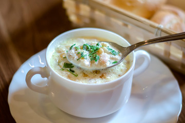 white cream soup in a white plate with crackers and herbs close-up