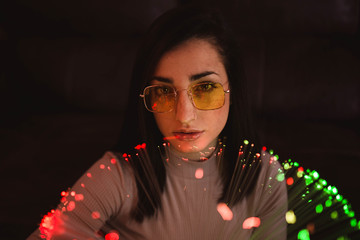 Young woman with fairy lights in darkness