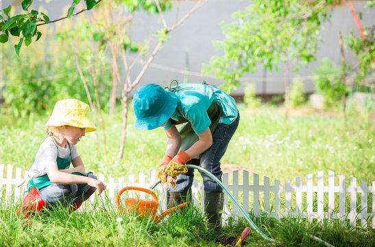 children gardening and watering plants in backyard