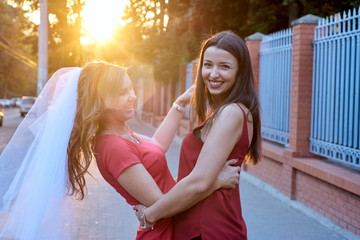Bride and bridesmaid laugh in the sun
