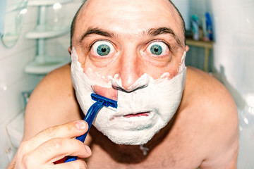 Crazy and insane man shaves in the bathroom, wide-angle photo.