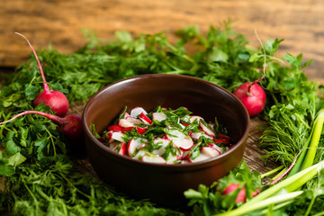 radish salad with green onions in a clay plate on a wooden board