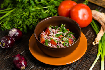 salad of tomato, onion and parsley with horseradish in an earthenware plate on a wooden board