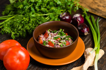 salad of tomato, onion and parsley with horseradish in an earthenware plate on a wooden board