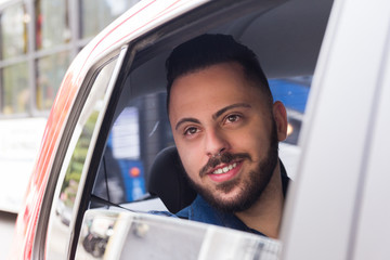 Happy bearded man looking through window in back seat of car. Concept of transport service, journey, motivation.