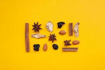 top view of collection of spices for mulled wine on yellow background. Сinnamon, anise, cloves, raisins, almonds