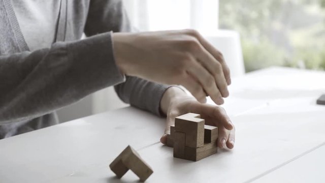 Woman solving an interlocking wooden puzzle