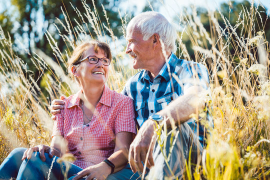 Paar aus Senioren Mann und Frau sitzt auf einer Wiese im Gras 