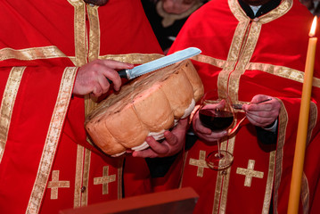 ortodox priests in red robes with holy bread in hands on ceremony