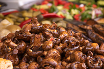 Fried Mushrooms Champignons on a plate on the background of a plate of chopped vegetables