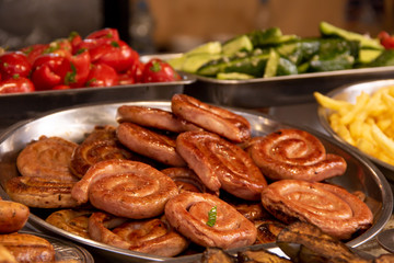 Roasted spiral sausages on a plate of greenery and vegetables in the background