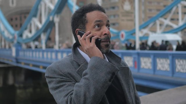 Black businessman in London takes a phone call on Tower Bridge