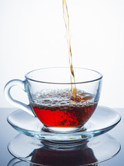 Hot tea is poured in a glass cup. Close up.