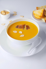 A bowl of spicy squash soup with bacon. Toasts and pumpkin seeds. High Key. Selective focus.