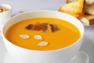 A bowl of spicy squash soup with bacon. Toasts and pumpkin seeds. High Key. Selective focus. Close up.