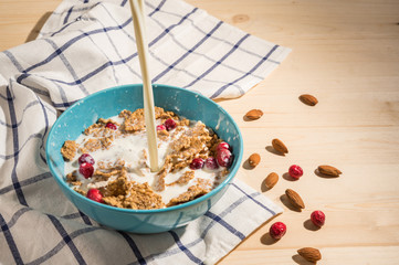 Milk pouring into bowl of cereals with nuts