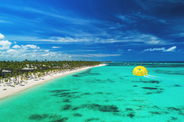 Tropical vacation in Punta Cana, Dominican Republic. Aerial view over beach resort. Parasailing.