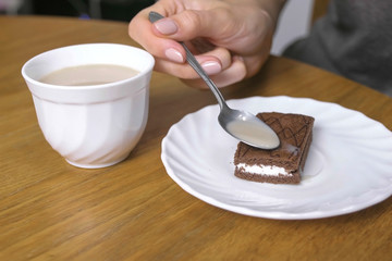 Woman pouring coffee on the piece of chocolate cake. Close-up hand.
