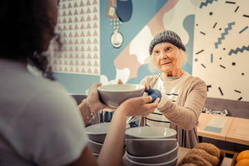 Pleasant hungry woman taking a bowl with soup