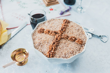 Orthodox cooked wheat in a bowl with walnuts next to glass of red wine and cresset prepared for a holy day