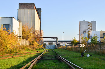 Obraz premium Railway tracks in the industrial zone of the plant. View of the building of the elevator of the bakery