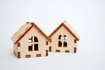 Two wooden toy houses on white background, one house stands behind the other, concept for selling houses with copyspace